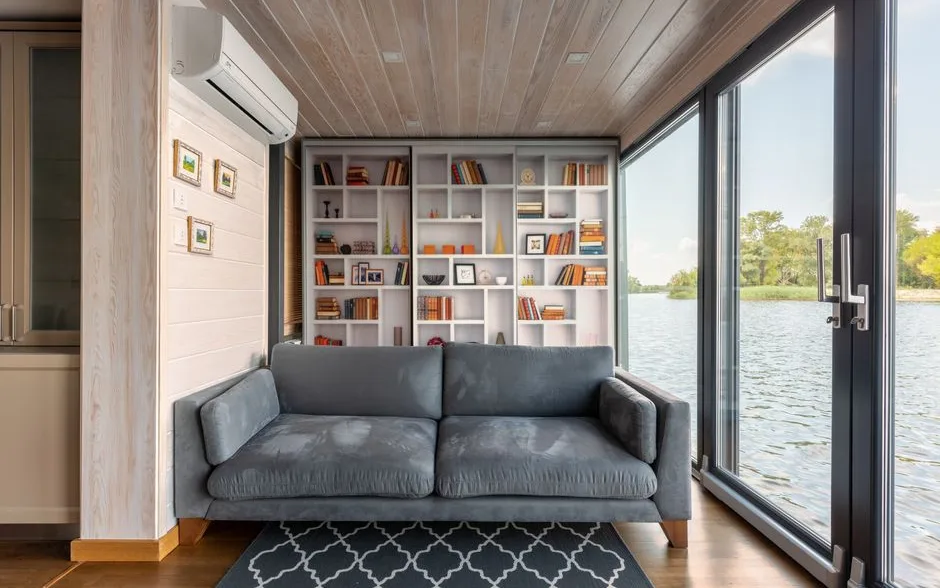 Séjour lumineux avec canapé gris et grande bibliothèque